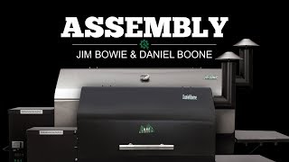 Jim Bowie and Daniel Boone pellet grills with prominent "ASSEMBLY" text, showcasing Green Mountain Grills products for instructional video content.