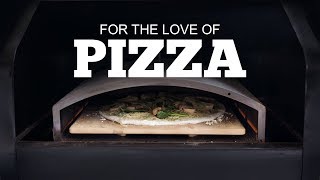 Wood-fired pizza cooking in a Green Mountain Grill oven with text overlay "FOR THE LOVE OF PIZZA."