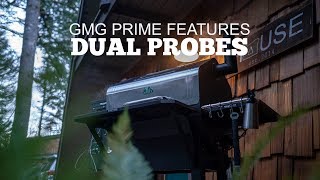 GMG Prime pellet grill showcasing dual probes, set in a natural outdoor environment with greenery and wooden structure in the background.