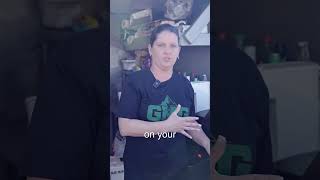 Woman demonstrating grilling techniques while wearing a Green Mountain Grills shirt, showcasing tips for using a pellet grill.