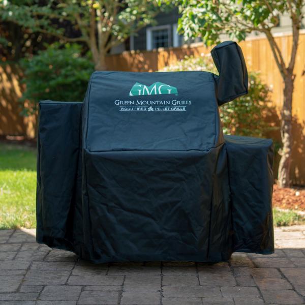 Black grill cover featuring Green Mountain Grills logo, designed for wood-fired pellet grills, positioned outdoors on a patio.